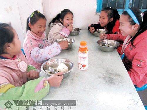 在融水苗族自治县香粉乡中心小学,一群六年级的小学生围坐在食堂里,吃着香喷喷的“免费午餐”。