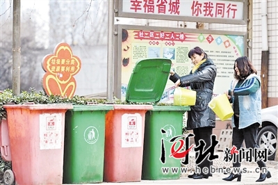 石家庄市神兴小区的居民正将生活垃圾倒入分类垃圾桶。